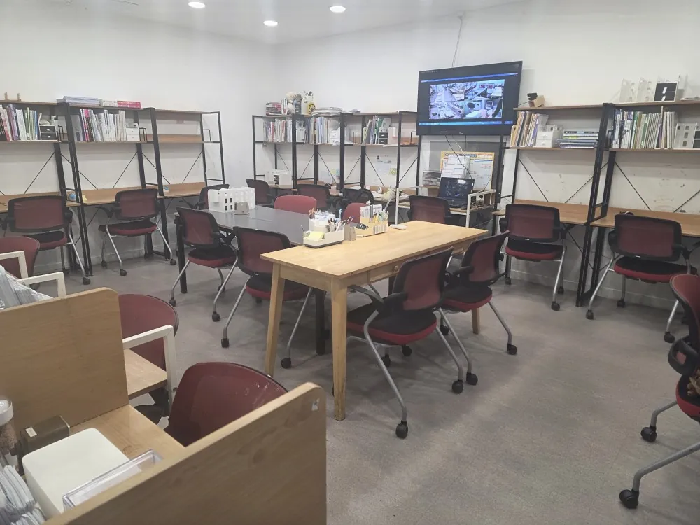 소주도관 내부. 검정 프레임 책장과 자주색 의자, 가운데 원목 테이블이 있다.